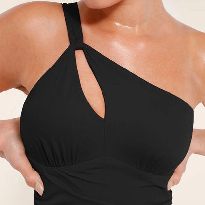 Koriģējošs melns peldkostīms ar asimetrisku dizainu un slaidinošu efektu, tuvplāns uz modeles